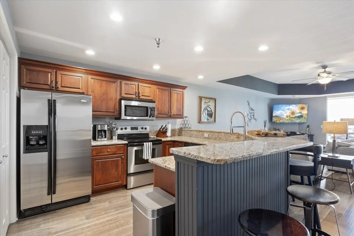 A warm, inviting kitchen scene with granite countertops, wood cabinetry, stainless steel appliances, and a bar seating area. The setup is ideal for socializing, entertaining, and shared meals, emphasizing the communal aspect of the home experience.