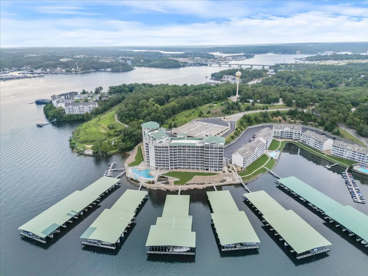 A scenic view of a large hotel building by calm waters, with boat docks and lush green landscaping. The calm water and nearby nature trails evoke a sense of adventure and exploration, inviting guests to experience the area's natural beauty and outdoor activities close to the property.